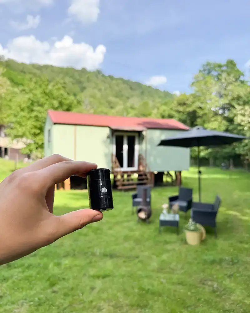 Lochkamera mit Natur und Haus im Hintergrund.