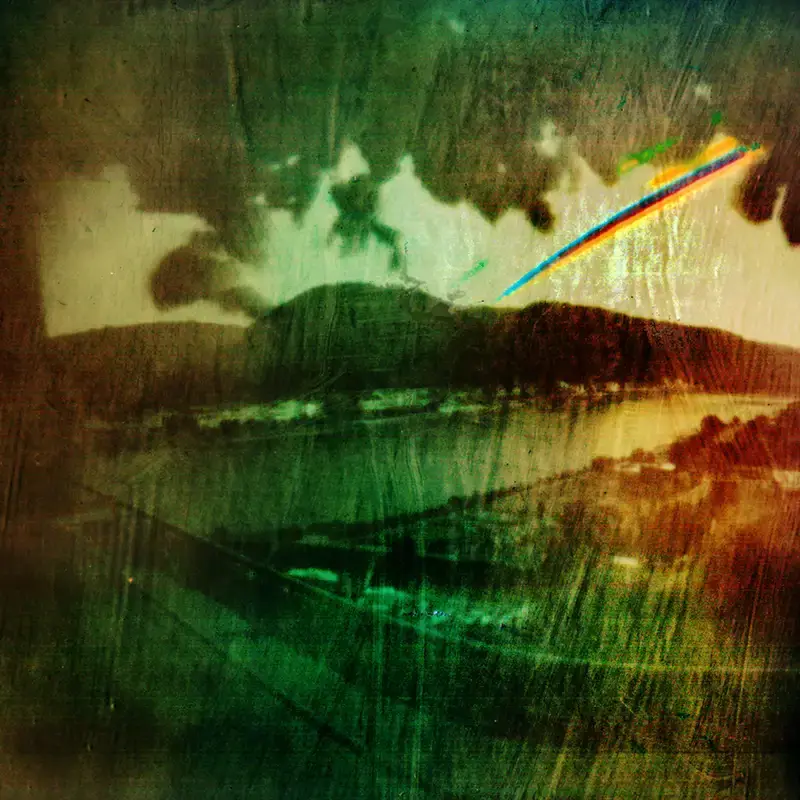 Mit der Lochkamera Fotografiertes Bild. Man sieht eine Sonnenspur vor Bergen